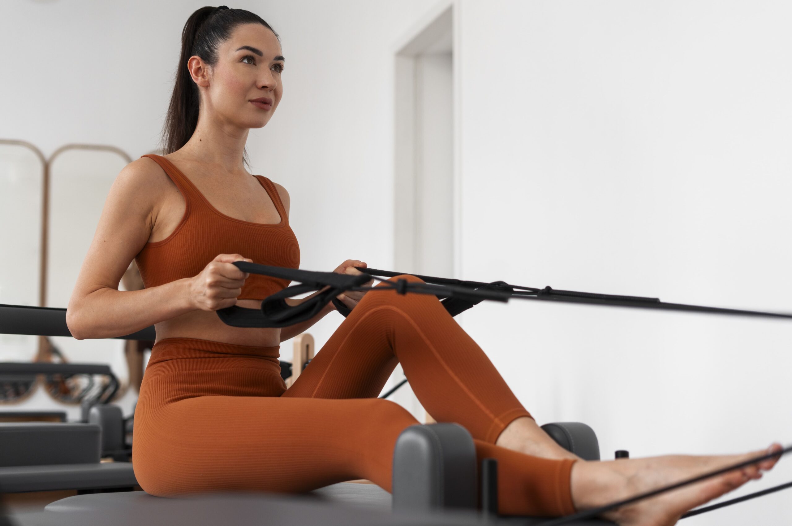full-shot-woman-taking-pilates-reformer-class-min